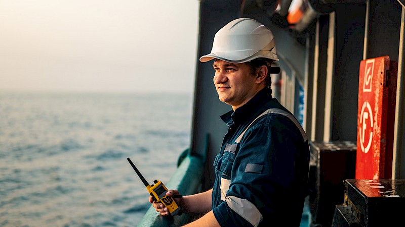 Employee leans against the rails of a vessel looking out to sea